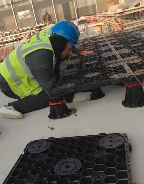 Worker installing outdoor paved patio on Vitaro pedestal grid