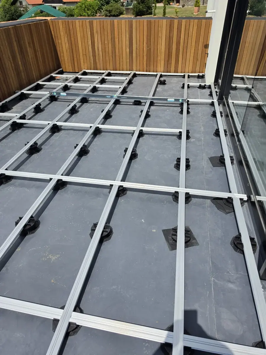 Pedestal grid leveled end-to-end across a Slovenia mansion rooftop with spirit level on site